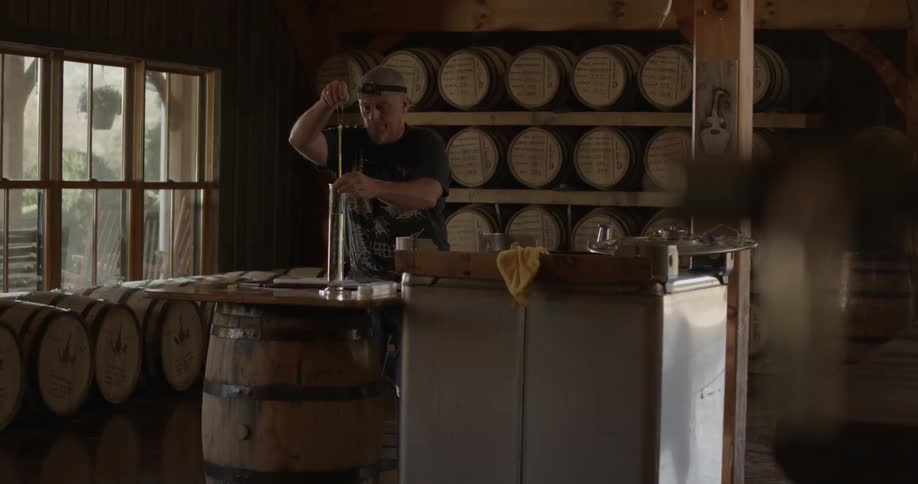 A man in a distillery checks the liquid in a tube