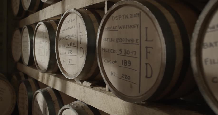 Barrels of whiskey cover shelves in a distillery