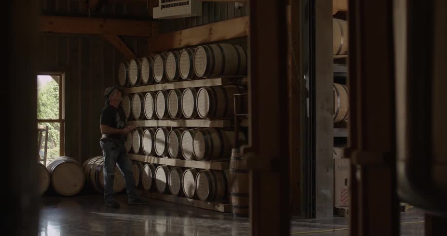 A man is taking inventory in a distillery