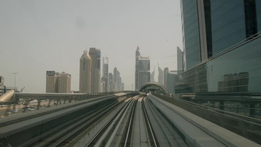 A city train moves along a track with skyscrapers in the distance
