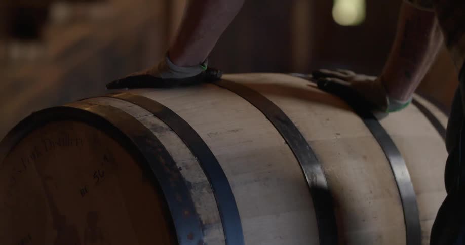 Man rolling a barrel indoors while wearing gloves