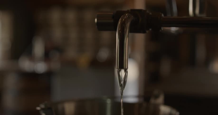 Clear liquid pours from a spigot into a bucket