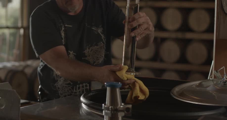 Man wipes off the bottom of a beaker filled with clear liquid