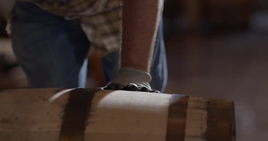A man uses gloves as he pushes a barrel
