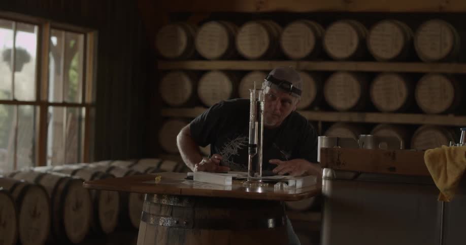 Man writing on a tabletop that is sitting on a barrel