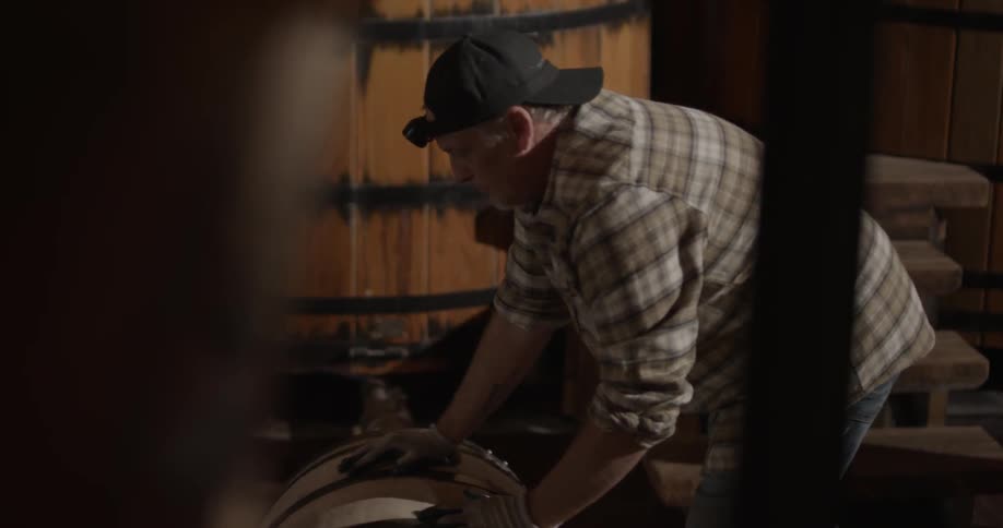 A man rolls a barrel through a room