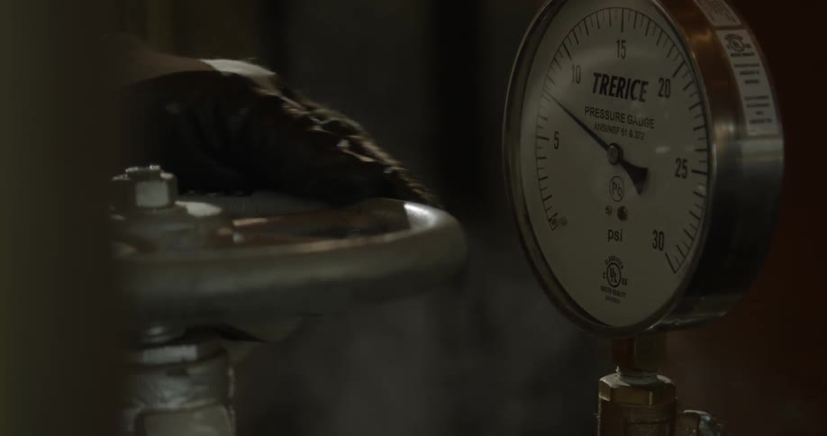 Person turns a metal wheel with steam rising up