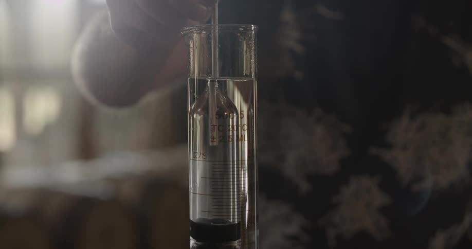 Man puts a vial with liquid in it in a tall glass beaker