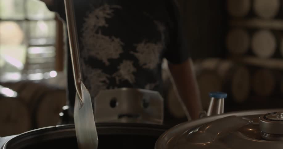 Man stirs in a large kettle with a metal oar