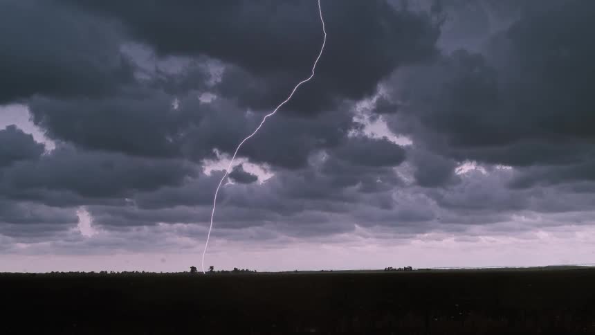 Lightning stabs the ground from storm clouds at dusk or dawn
