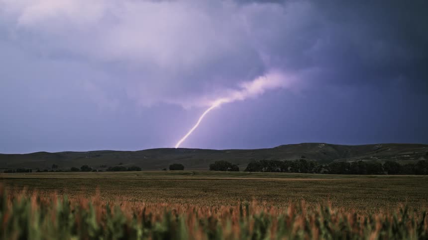 A large flash of lightning hits the hills ahead