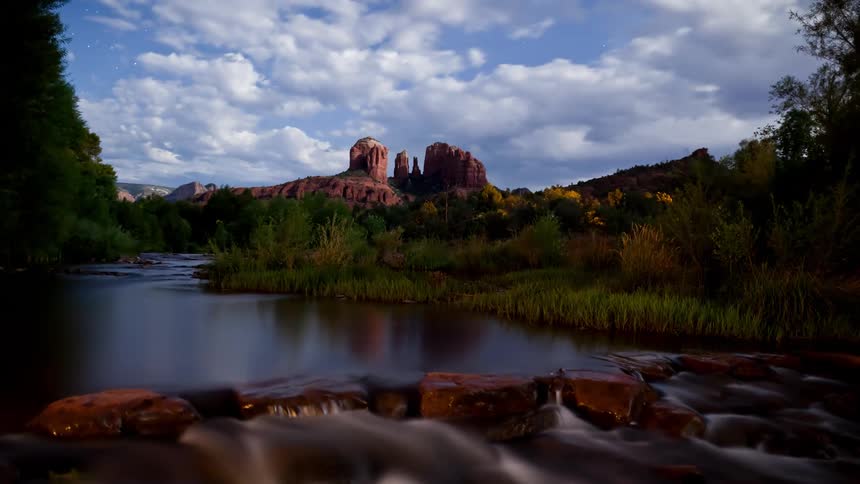 Clouds move across a flowing river during a full moon