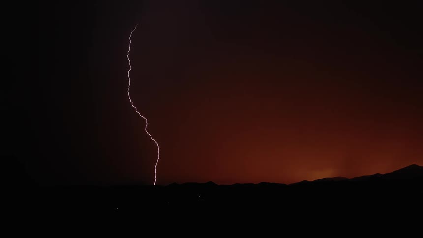 Lightning strikes a hill at sunset