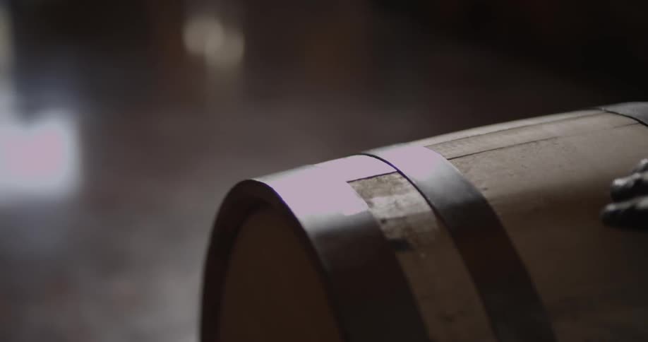 A person rolls a large wooden barrel across a floor