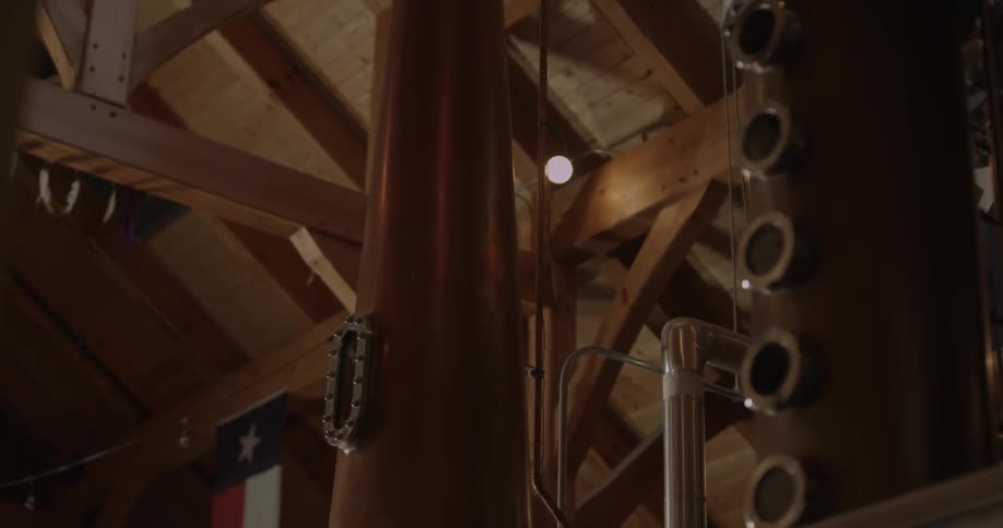 A tall still is made of brass and goes to the ceiling