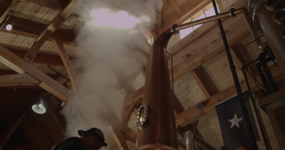 A man opens a still and heavy steam rises