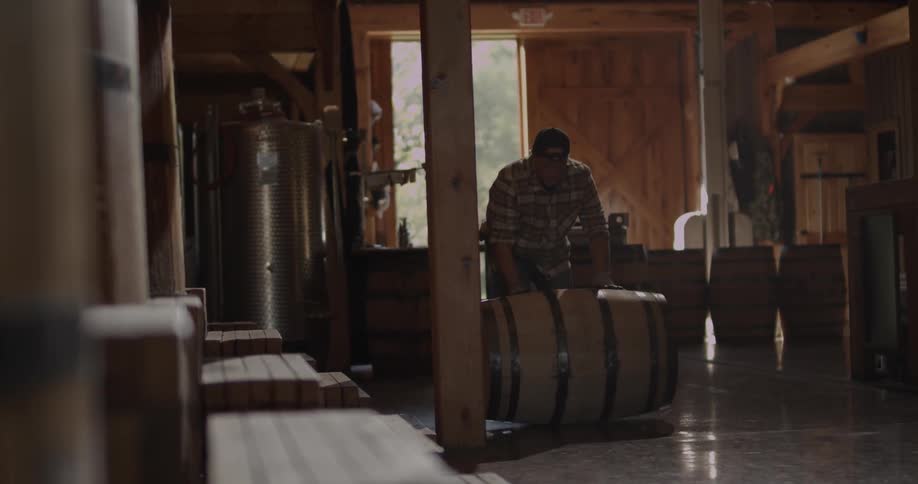 A man rolls a barrel across the distillery floor