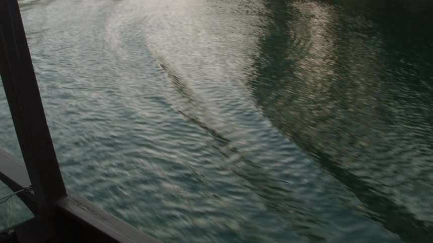 A boat leaves a wake and ripples as it moves in a river