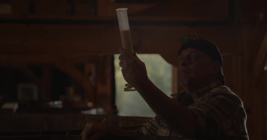 A man makes some measurements with the beer in a distillery