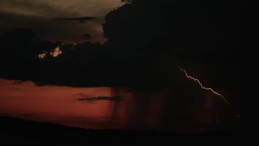 A storm moves across the sky trailing lightning and rain