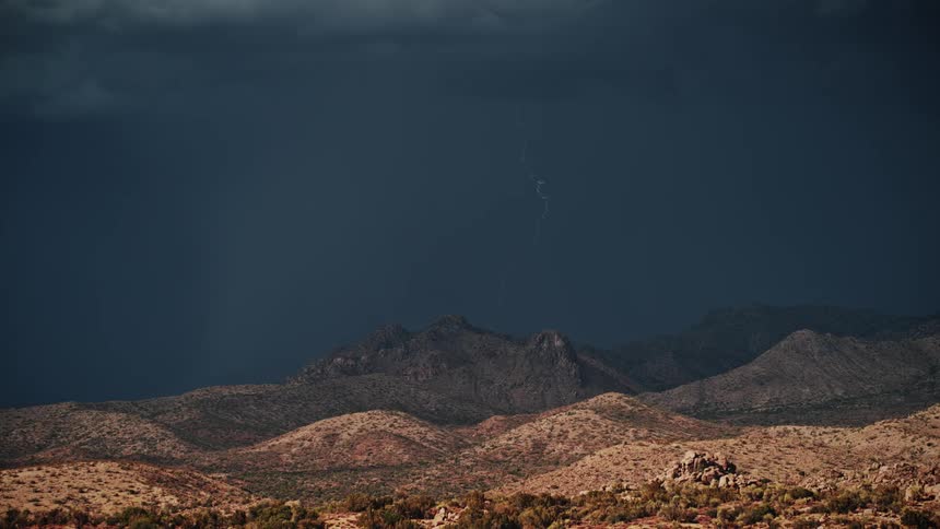 Rain is pouring over the mountains ahead with some lightning