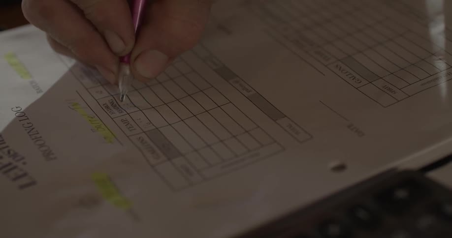 A man fills out paperwork with a pencil