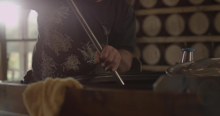 Man stirs in a kettle with a large metal stick