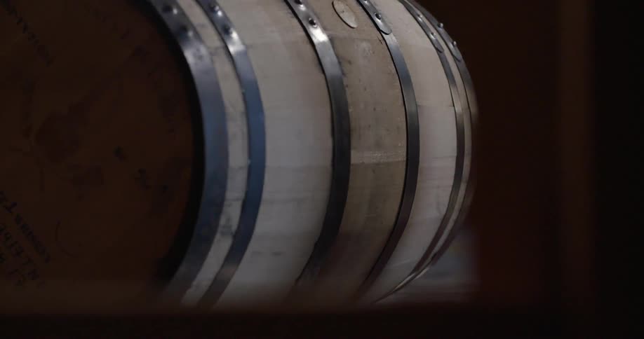 A large barrel is being pushed in a distillery