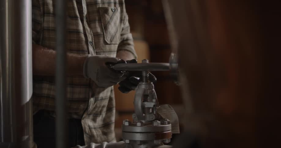 A man is turning a large valve on a machine