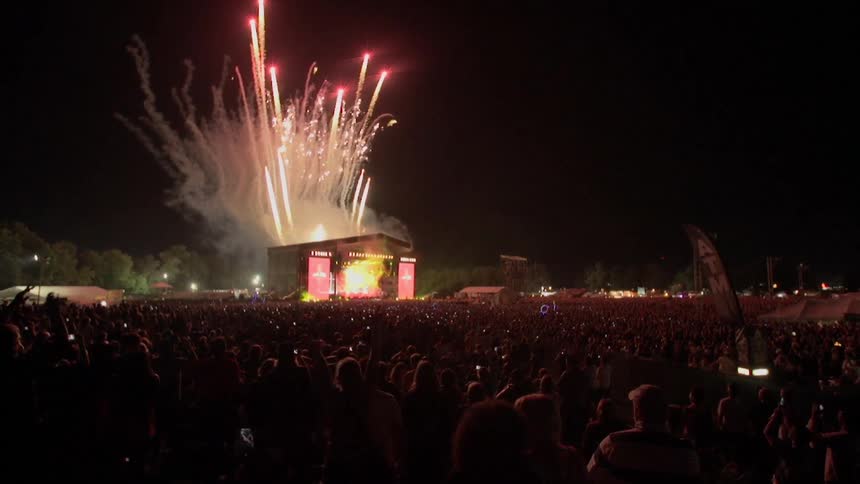 View of a large crowd of people as fireworks go off in the background