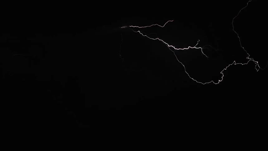 A large storm cloud shoots lightning in all directions lighting up the night sky