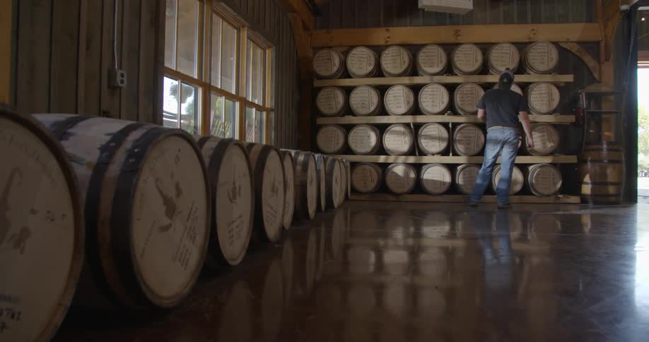 A man is counting barrels in a distillery