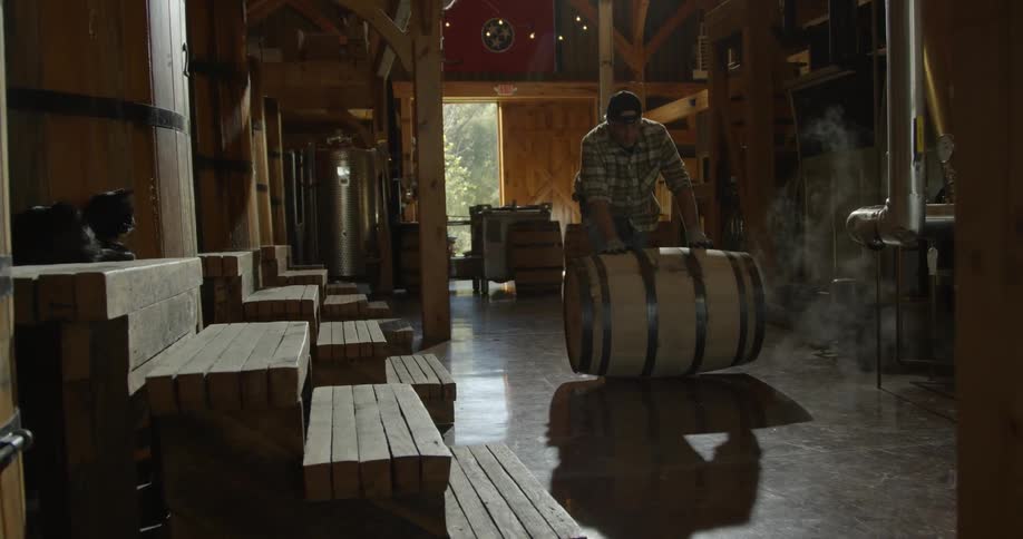 A man is pushing a barrel in a distillery