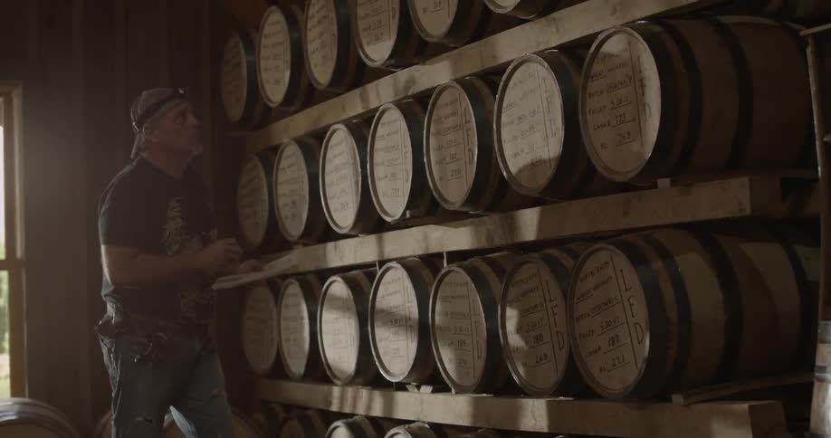 Man writes on clipboard looking at a wall of barrel