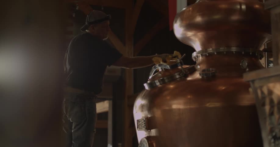 A man cleans equipment in a distillery