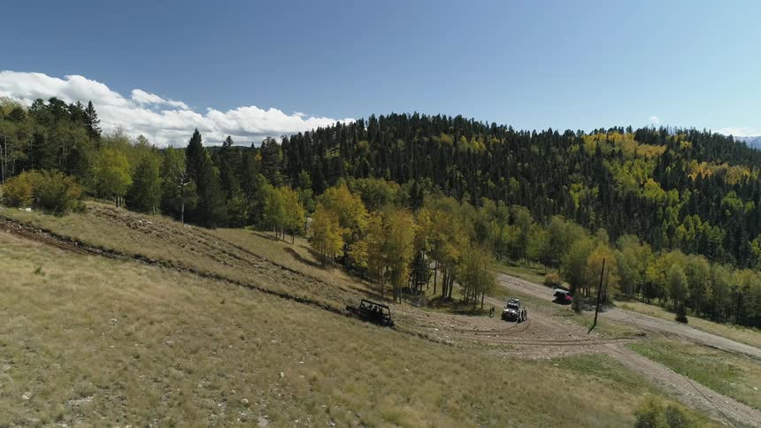 Car driving down a grassy hill in the country