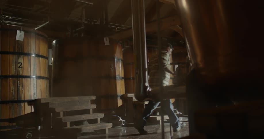 A man climbs down wooden steps in a distillery