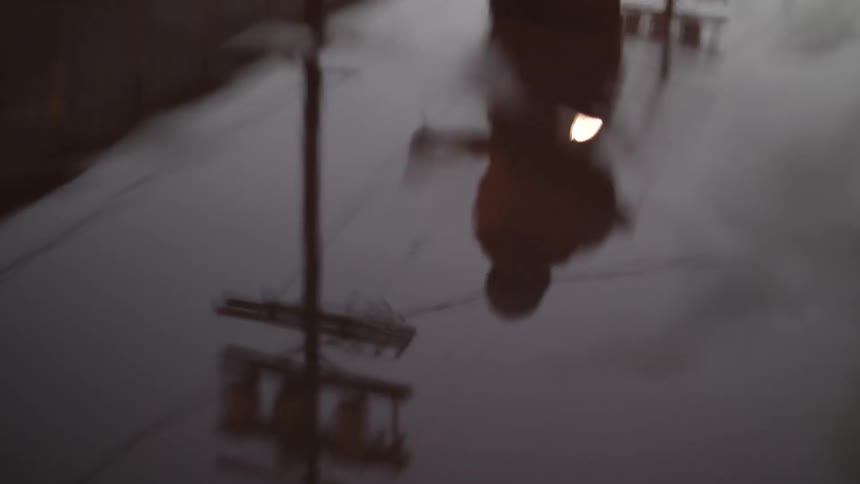 A man jumping rope outside is reflected by a puddle of water