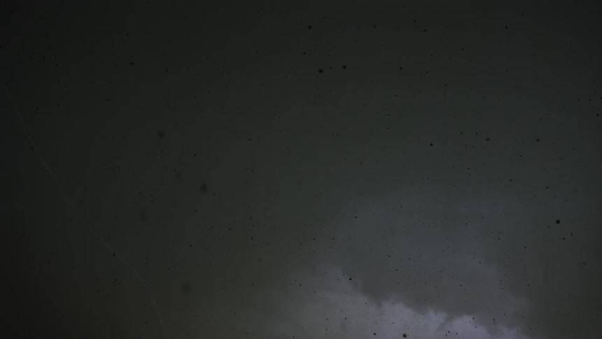 Lightning flashes in dark clouds as particles fall from the sky