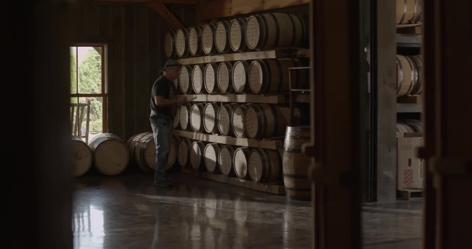 Man writes on clipboard looking at a wall of barrels