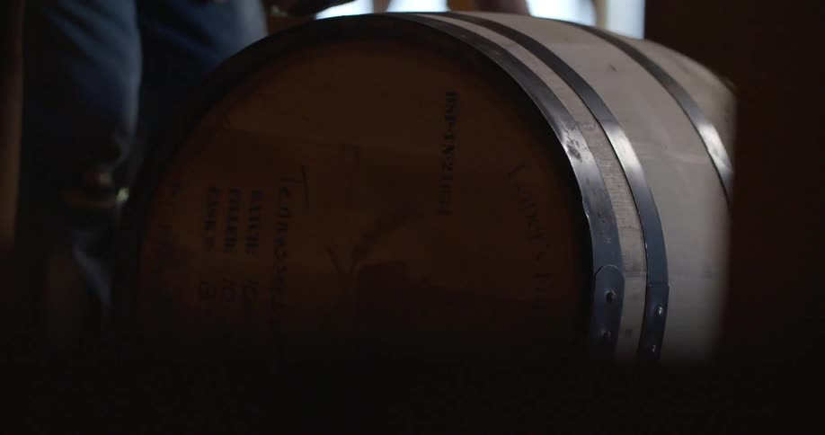 A man roles a barrel in a warehouse
