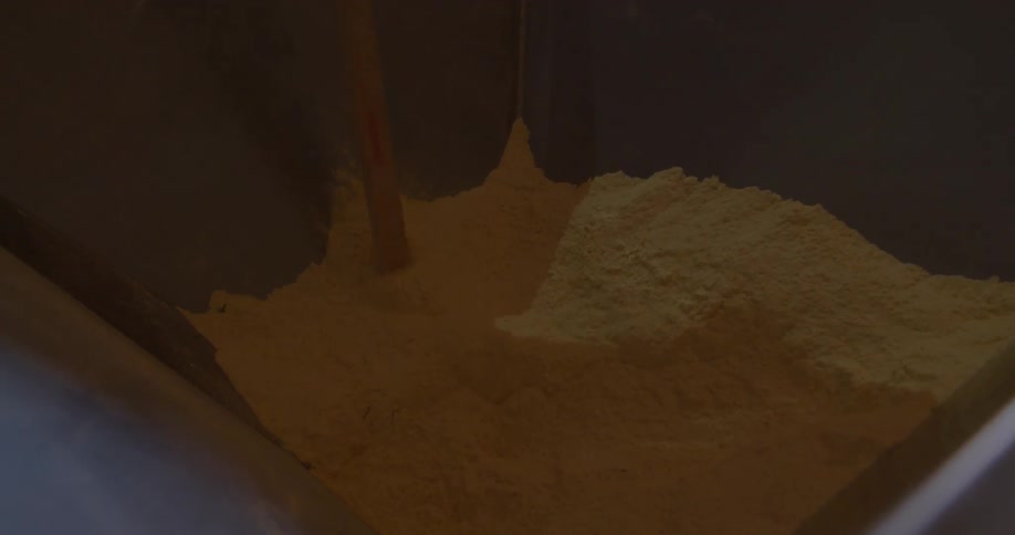 A stick is used to stir powder in a large container