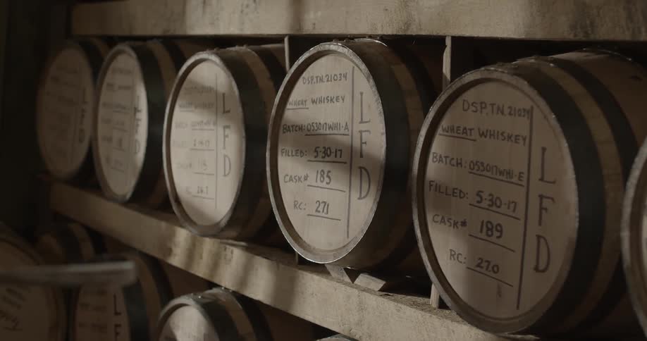 A man inspects barrels of whiskey in a distillery