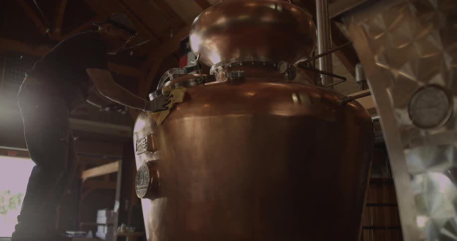 A man polishes a large still in a distillery