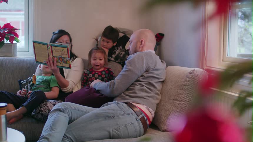 A man and woman read to children on a couch