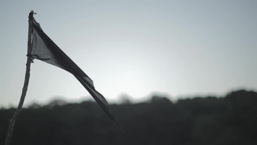 Torn piece of fabric tied to stick blows in the wind