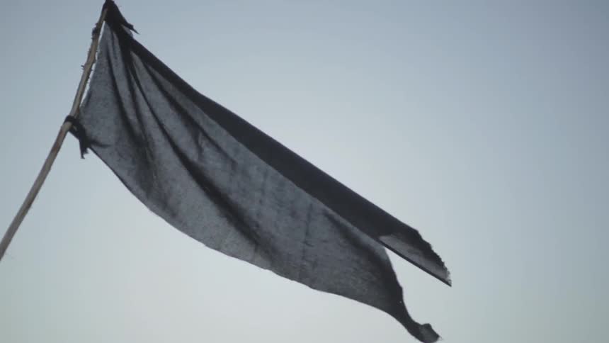 A black flag flies in the wind outdoors
