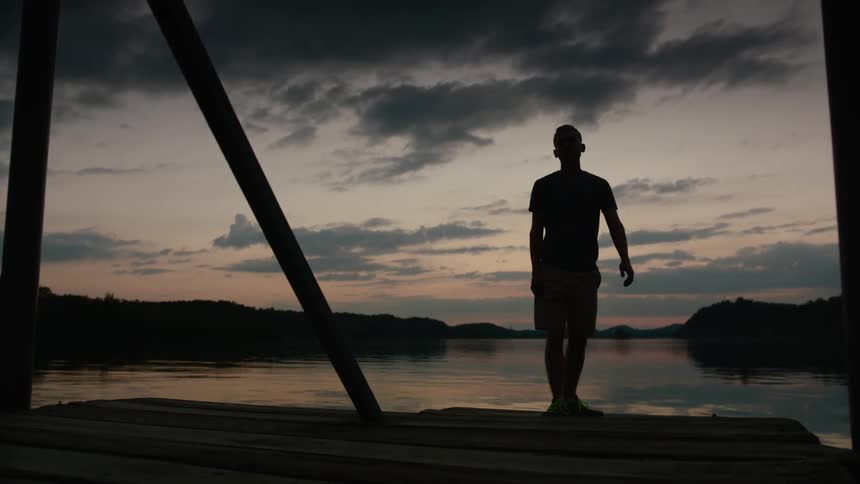 Silhouette of a man standing on a dock at sunset