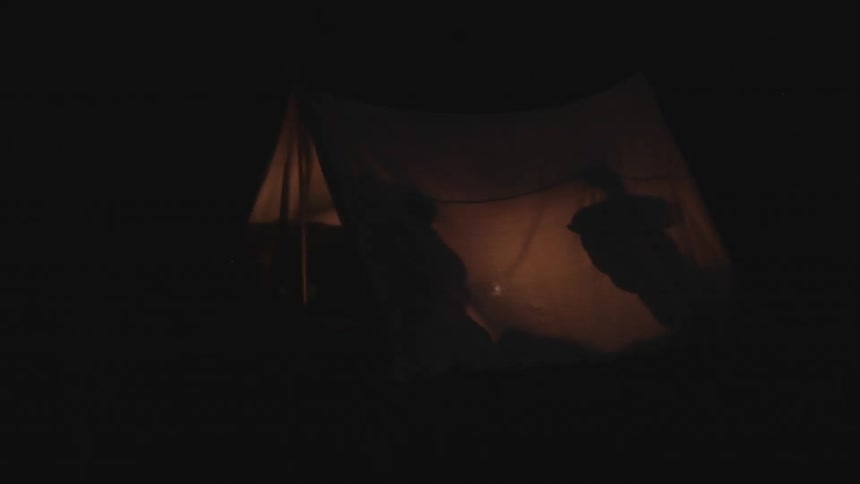 Silhouettes of campers in a tent at night