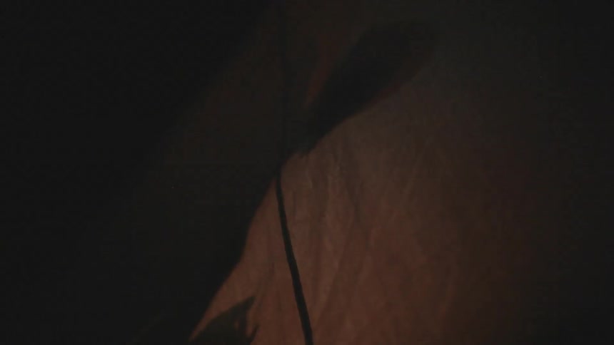 A silhouette of a person inside of a tent